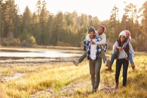 Parents giving children piggyback ride on walk by lake